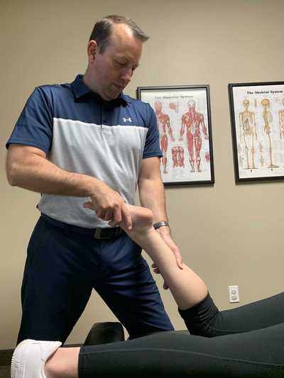 Dr. Carter at InMotion chiropractic Buffalo Minnesota performing active release on a patient’s lower leg.