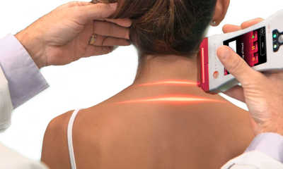 Dr. Carter at InMotion chiropractic Buffalo Minnesota performing cold laser on a patient’s neck.